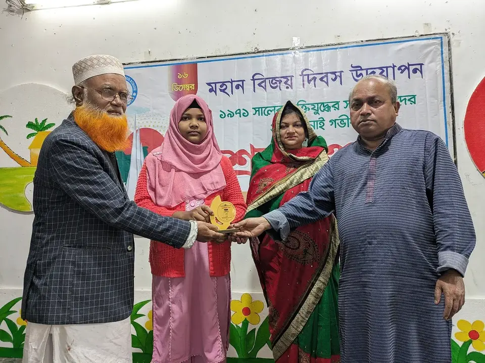 মহান বিজয় দিবস উদযাপন অনুষ্ঠানে একজন শিক্ষার্থীর হাতে পুরস্কার তুলে দেওয়া হচ্ছে